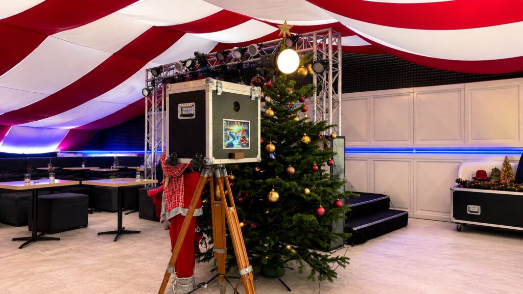 Fotoautomat neben geschmücktem Weihnachtsbaum bei einer Weihnachtsfeier
